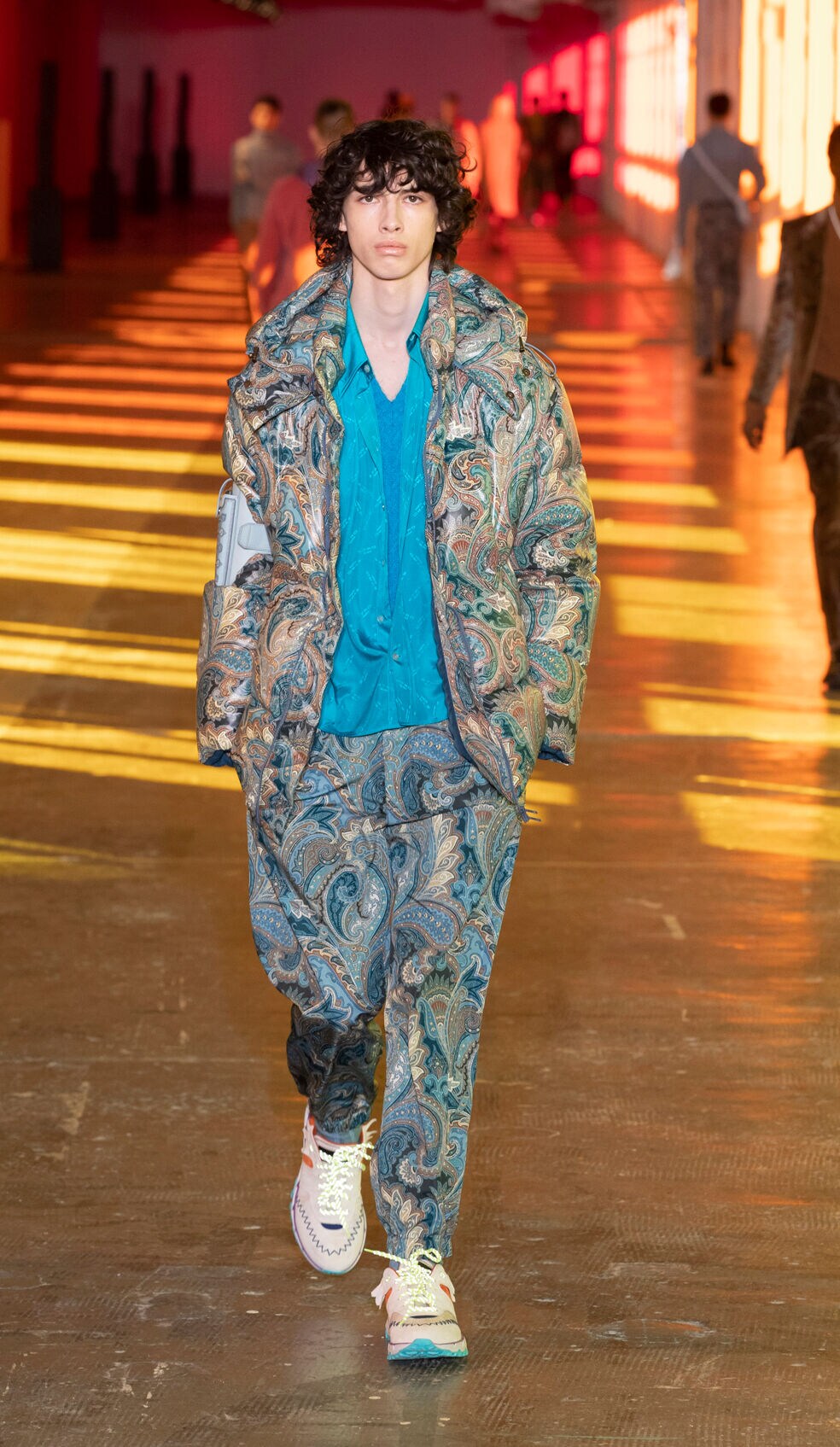 Ein Model auf dem Laufsteg, er trägt einen blauen Look mit Paisleymuster.