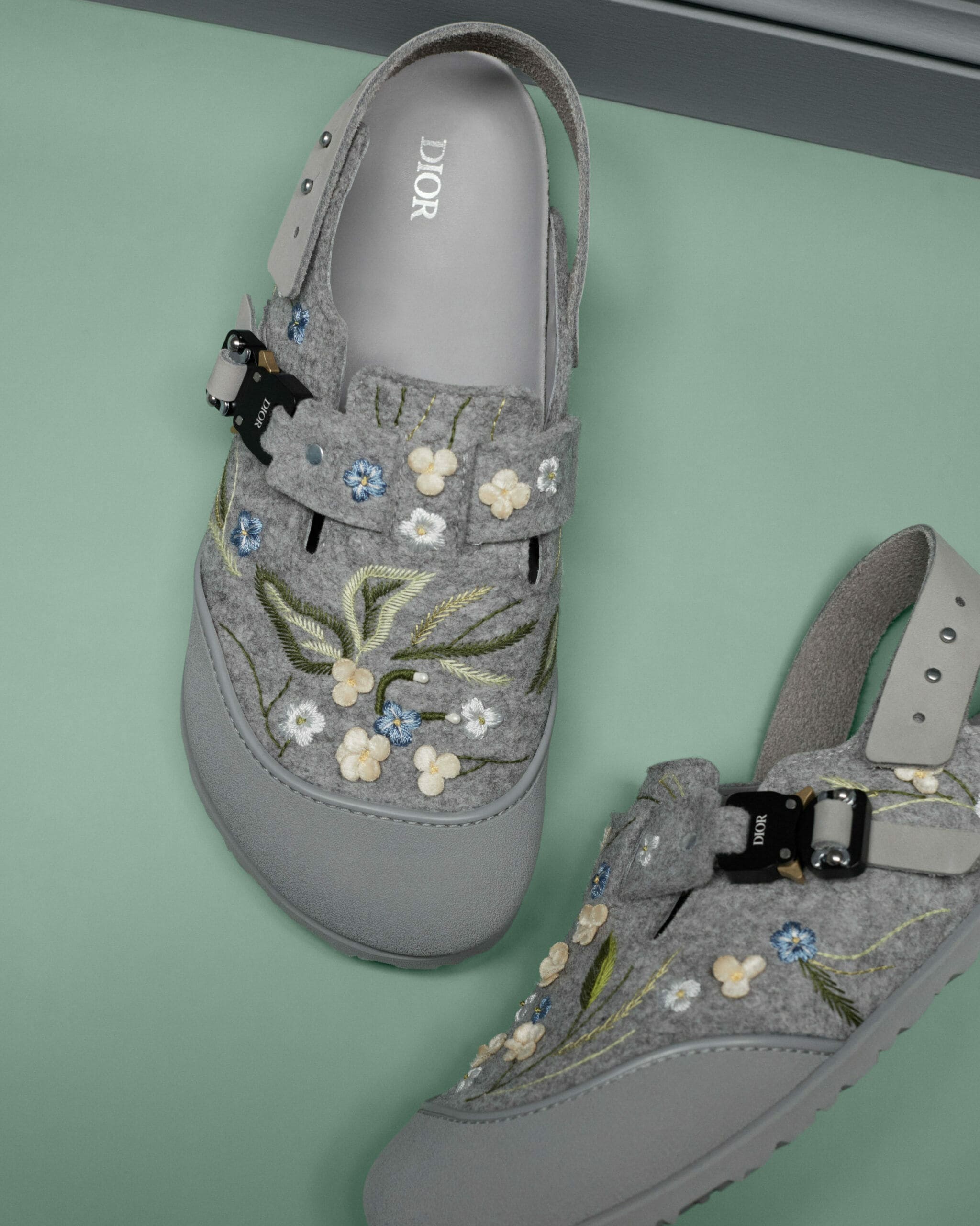 Detailaufnahme einer grauen Filz-Sandale mit Blumenstickerei und Dior-Logo