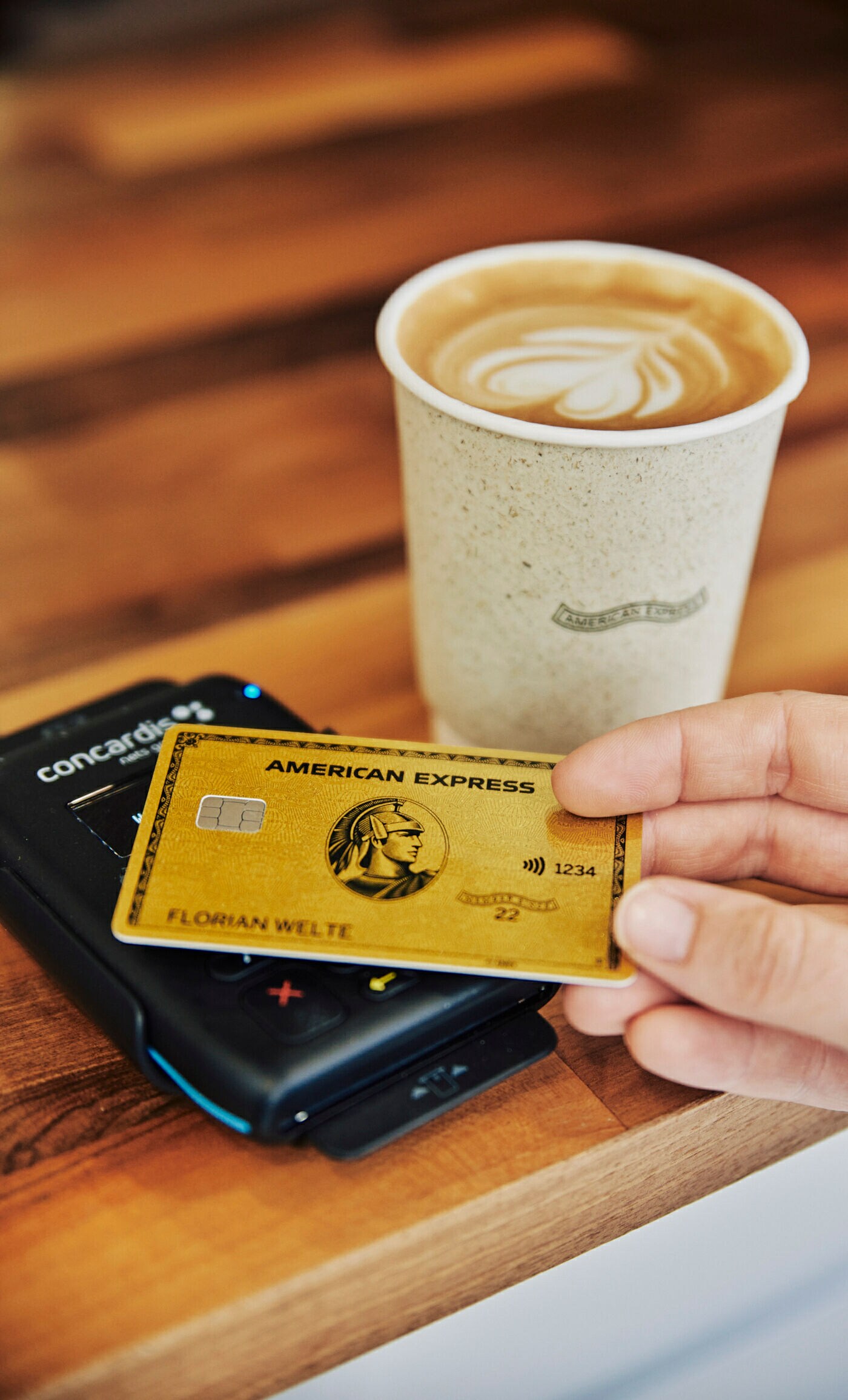 Person bezahlt kontaktlos einen Kaffee mit einer American Express Gold Card