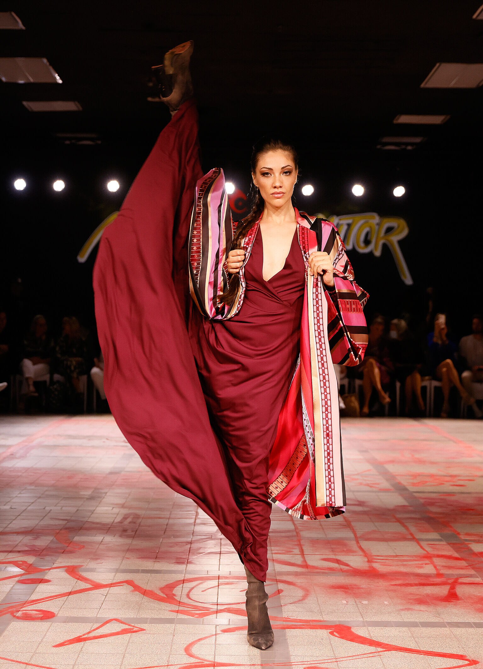 Ein Model in rotem Kleid auf einem Catwalk in spektakulärer Pose