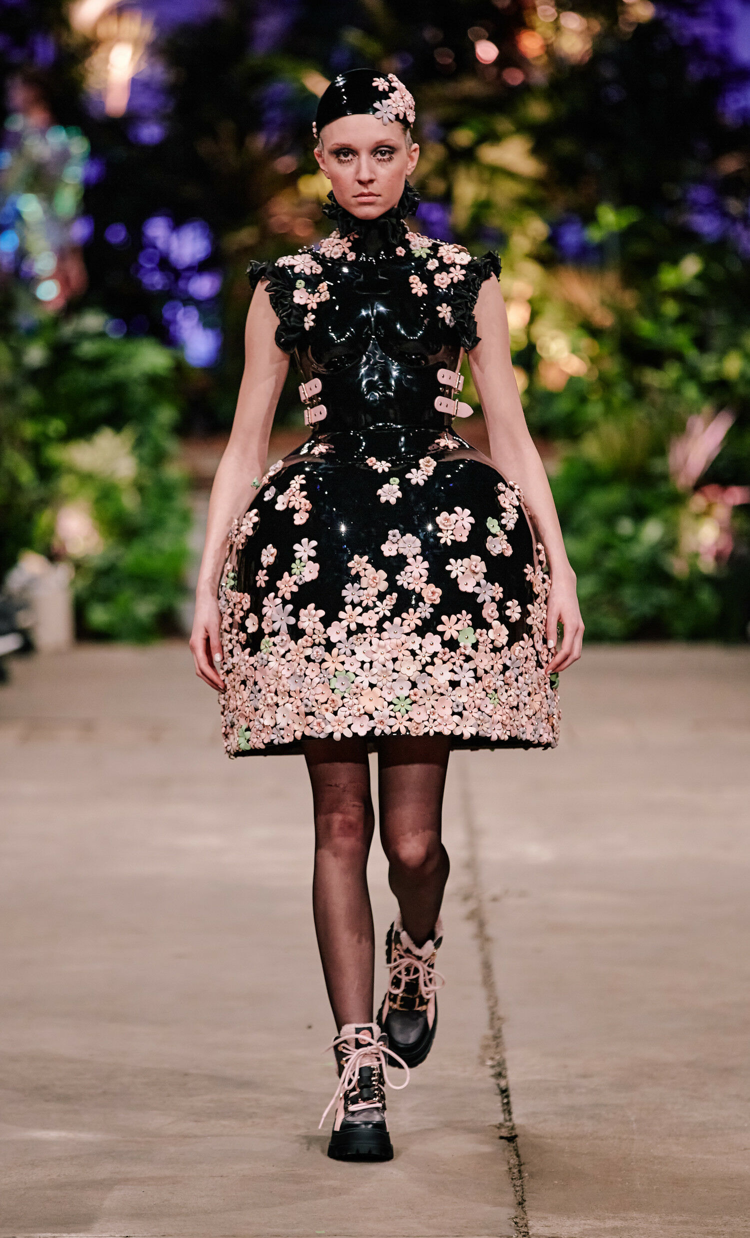 Ein Model in einem extravaganten Kleid mit Blumenmuster läuft auf einem Catwalk