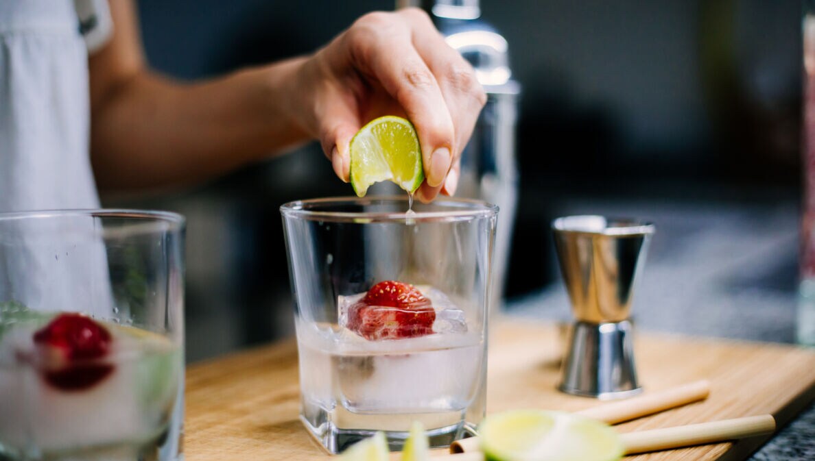 Gin-Getränk mit einer Erdbeere im Eiswürfel und Limette