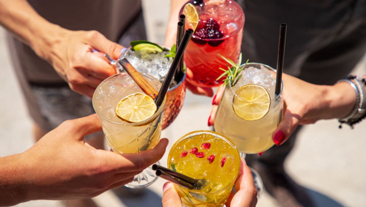 Fünf Hände halten Gläser mit fruchtigen Drinks
