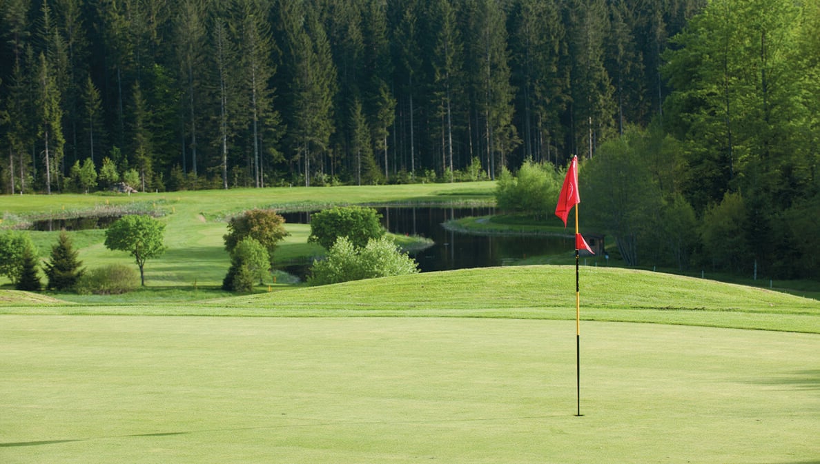 Eine rote Fahne auf dem hügeligen Golfplatz