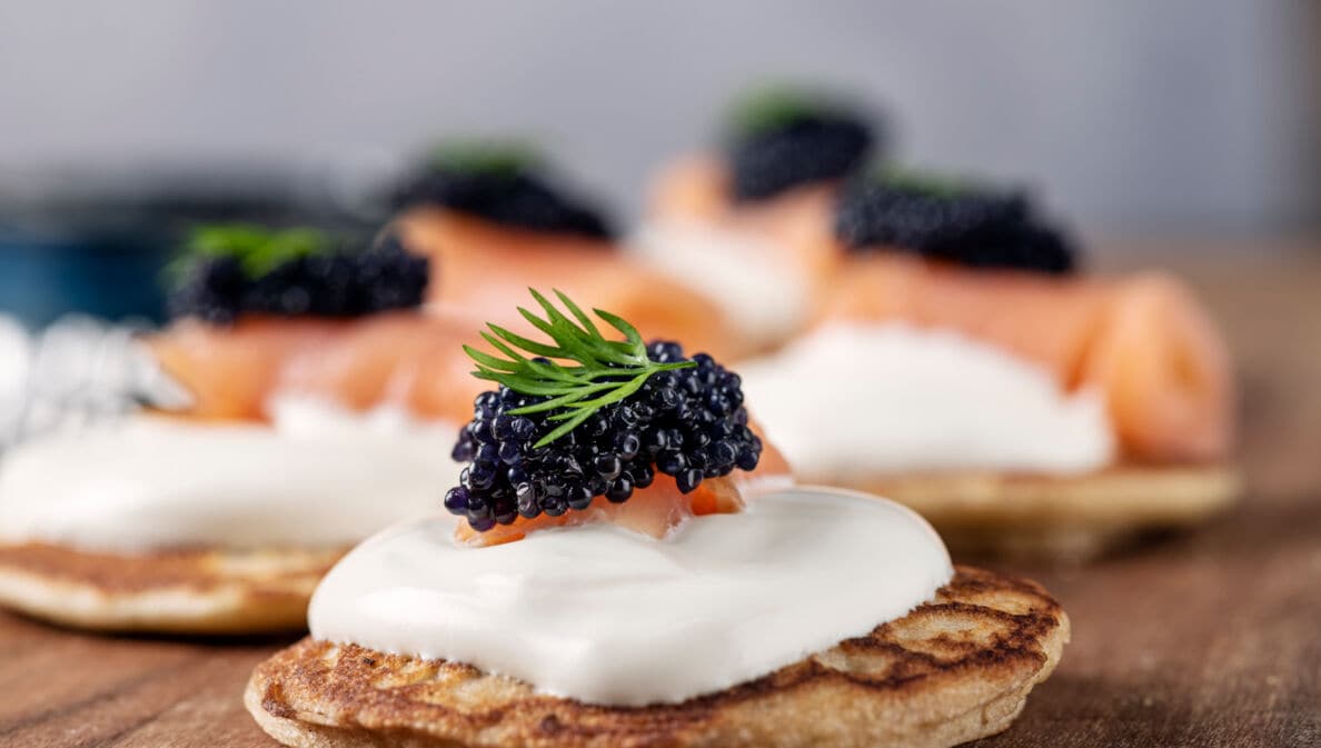 Ein kleiner Kartoffelpuffer mit Crème Fraîche und Kaviar