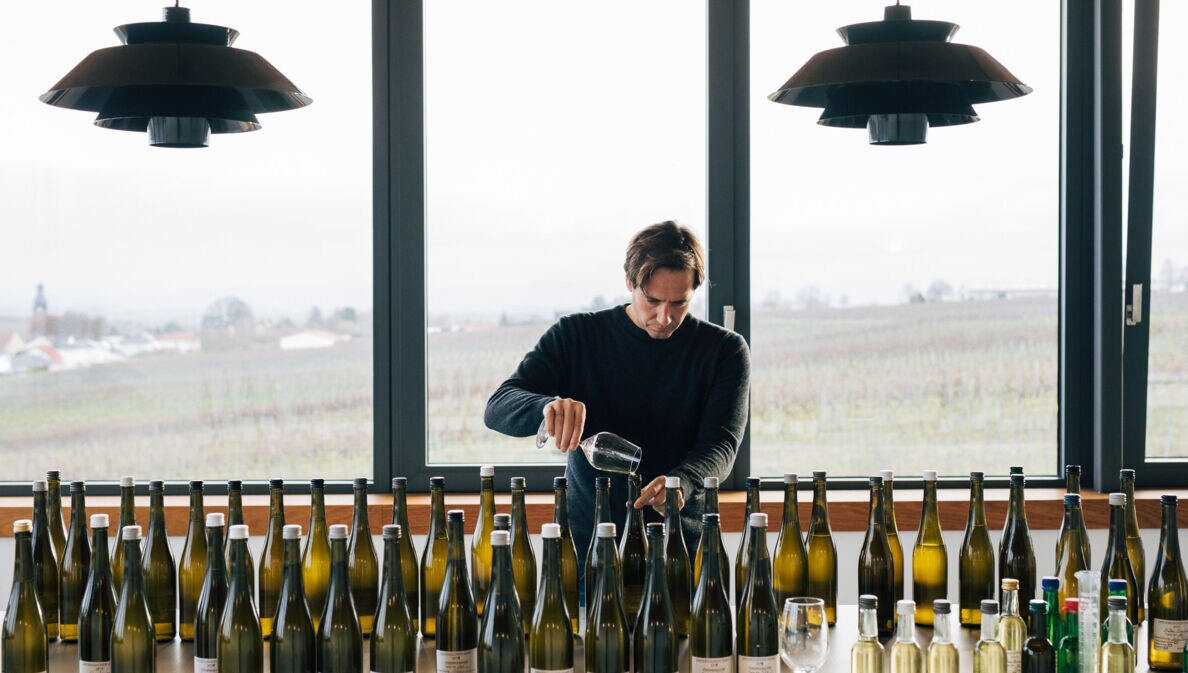 Winzer Jochen Dreissigacker beim Wein einschenken vor einem Tisch mit Weinflaschen