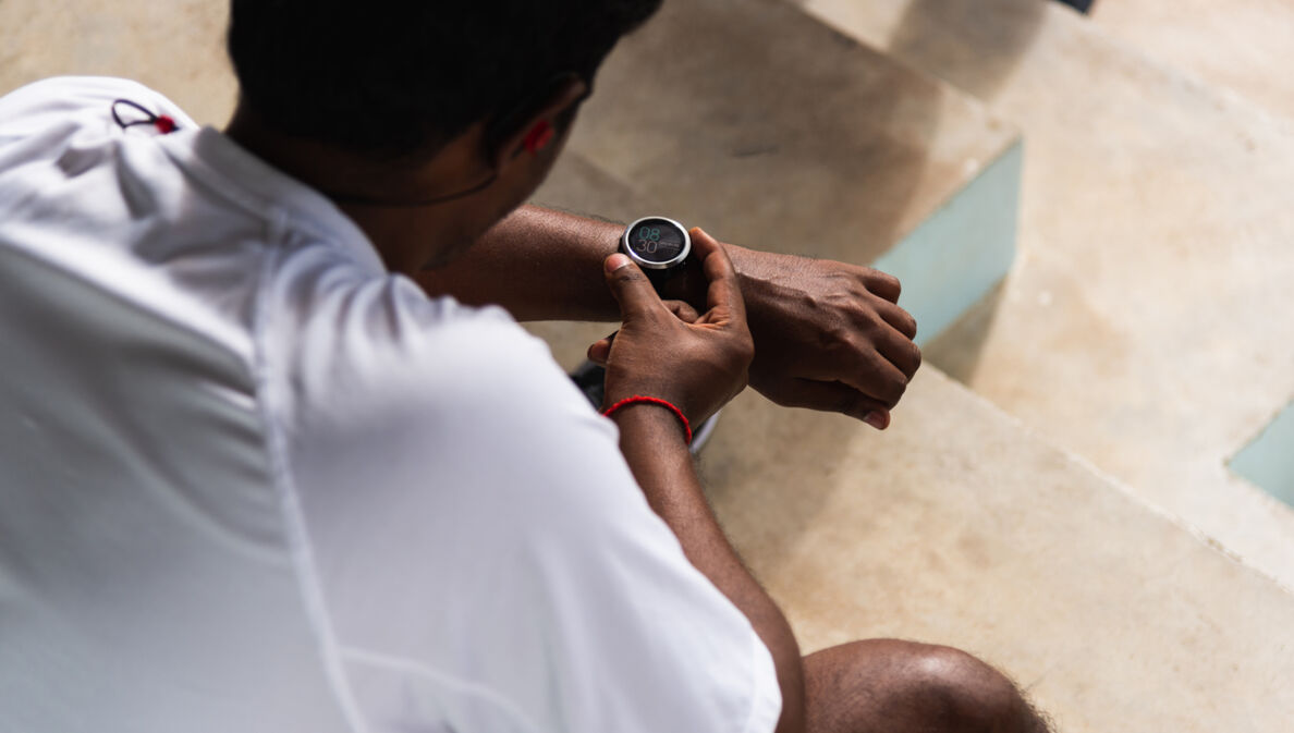 Ein Mann in Sportkleidung mit Armbanduhr mit Digitalanzeige am Handgelenk