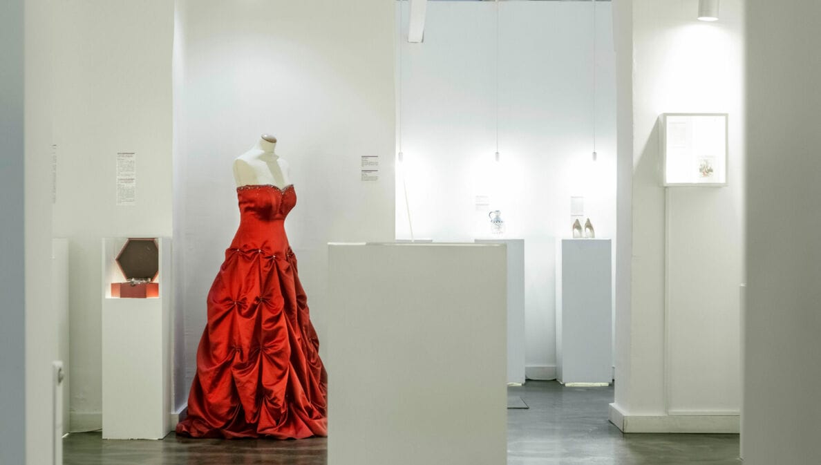 Ein rotes Abendkleid auf einer Schneiderpuppe in einem weißen Showroom