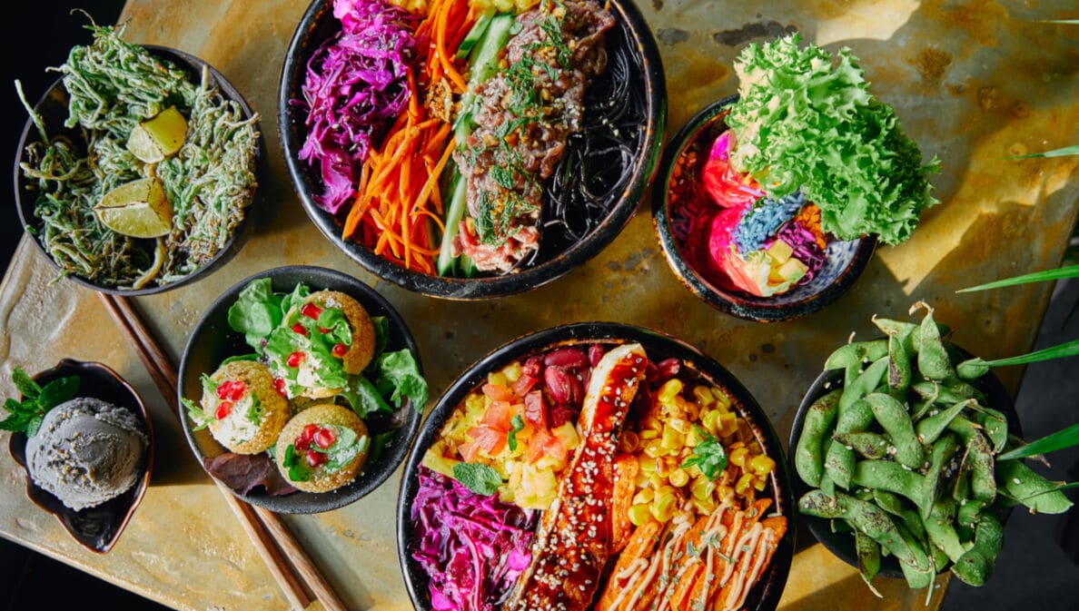 Verschiedene Speisen in leuchtenden Farben, die in Schalen auf einem Tisch angerichtet sind
