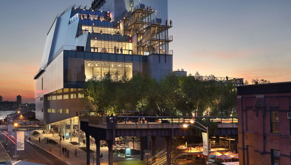 Beleuchteter, moderner Gebäudekomplex des Whitney Museum of Art mit Besuchern auf unterschiedlichen Terrassen in der Abenddämmerung