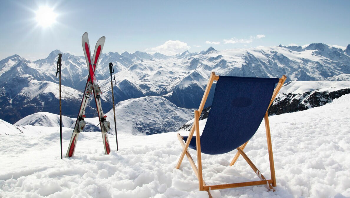 Ein Liegestuhl und Ski mit Stöcken auf einem Berg im Schnee