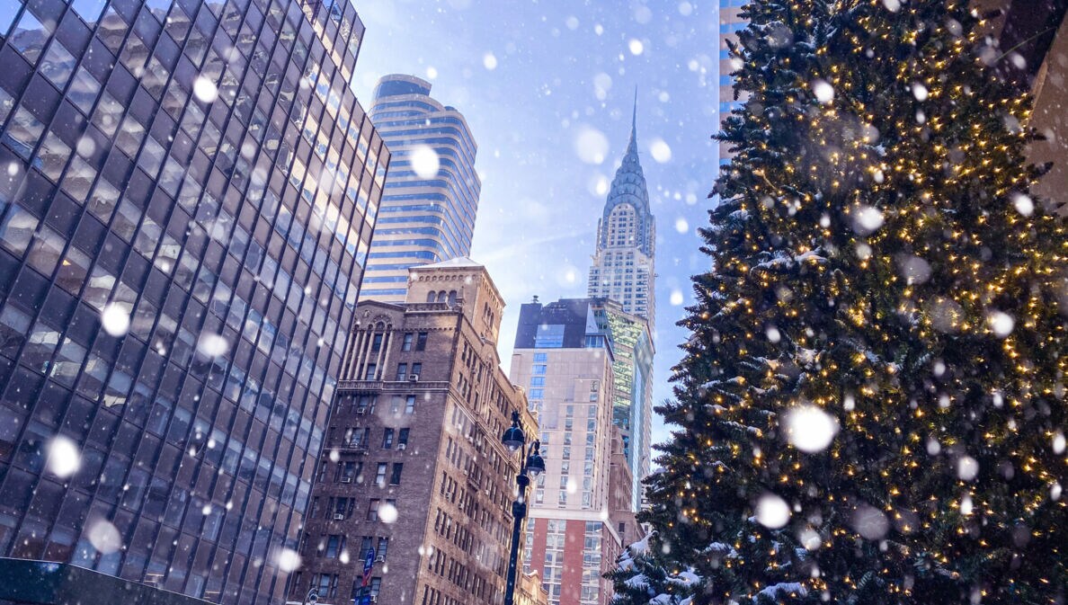 Häuserschlucht in Manhattan mit Blick auf Chrysler Building und Tannenbaum im Vordergrund bei Schneefall