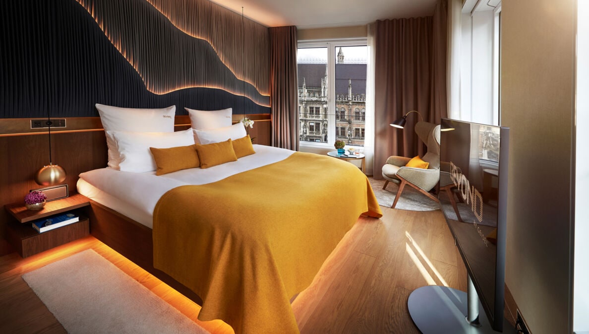 Modernes, stilvolles Hotelzimmer mit großem Doppelbett und Blick auf den Münchener Marienplatz