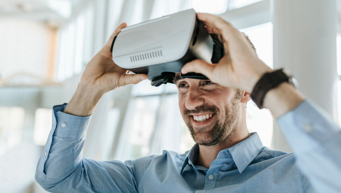 Ein junger Mann setzt eine VR-Brille ab.