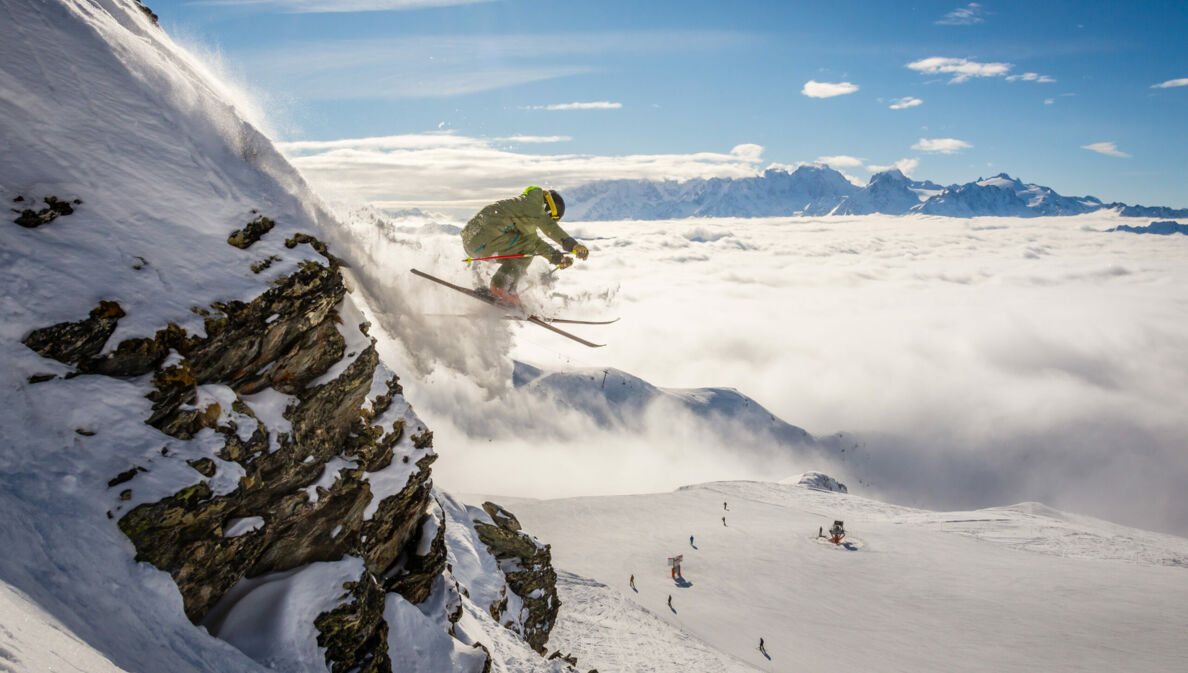 Eine Person auf Ski fliegt einen schneebedeckten Hang hinab