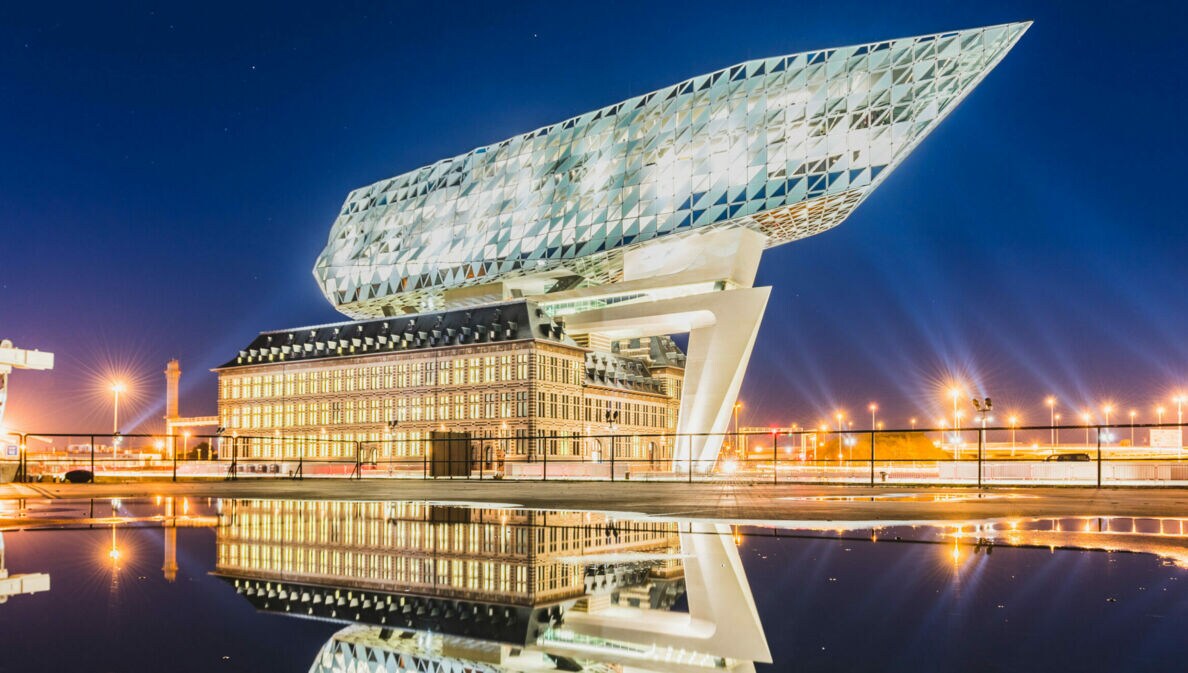 Ein futuristisches Bauwerk auf einem alten Gebäude, beide beleuchtet bei Nacht