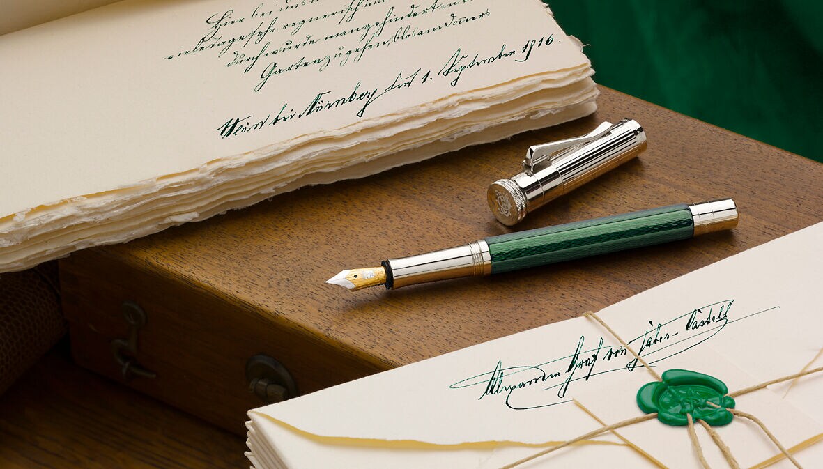 Ein grün-silberner Füllfederhalter auf hölzernem Untergrun zwischen zwei nostalgischen Briefstapeln