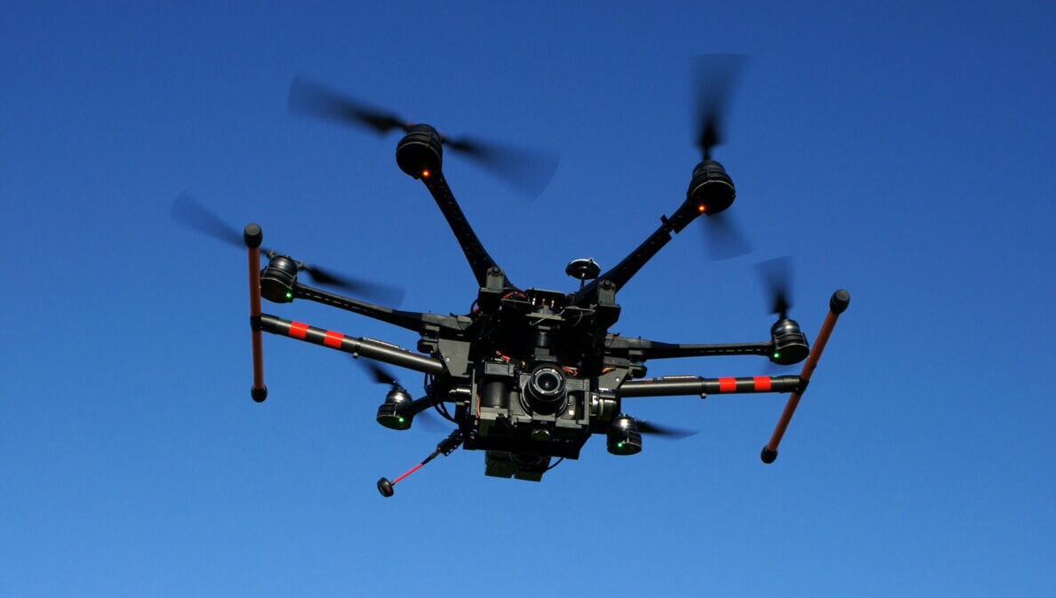Eine große Drohne mit Kamera vor blauem Himmel