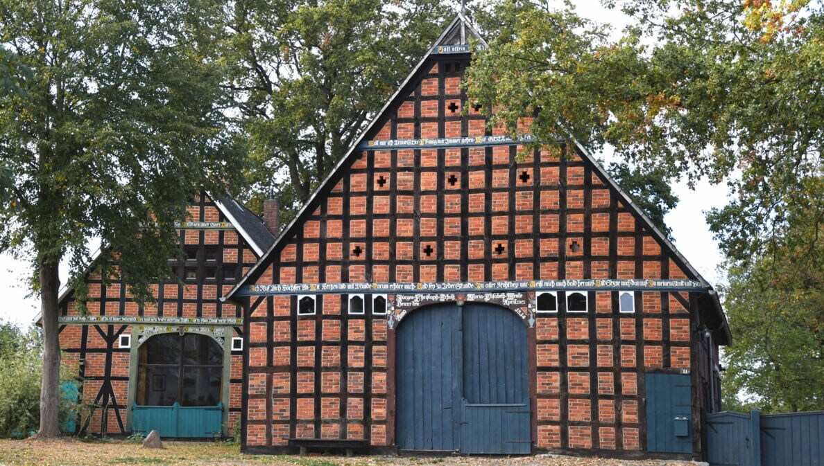 Zwei Fachwerkhäuser mit blauen Toren, daneben Bäume
