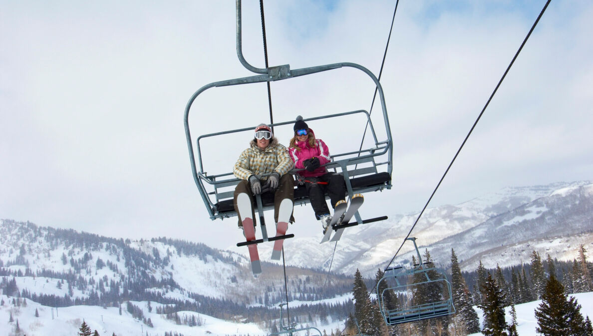 Ein Paar in Skikleidung fährt mit dem Skilift