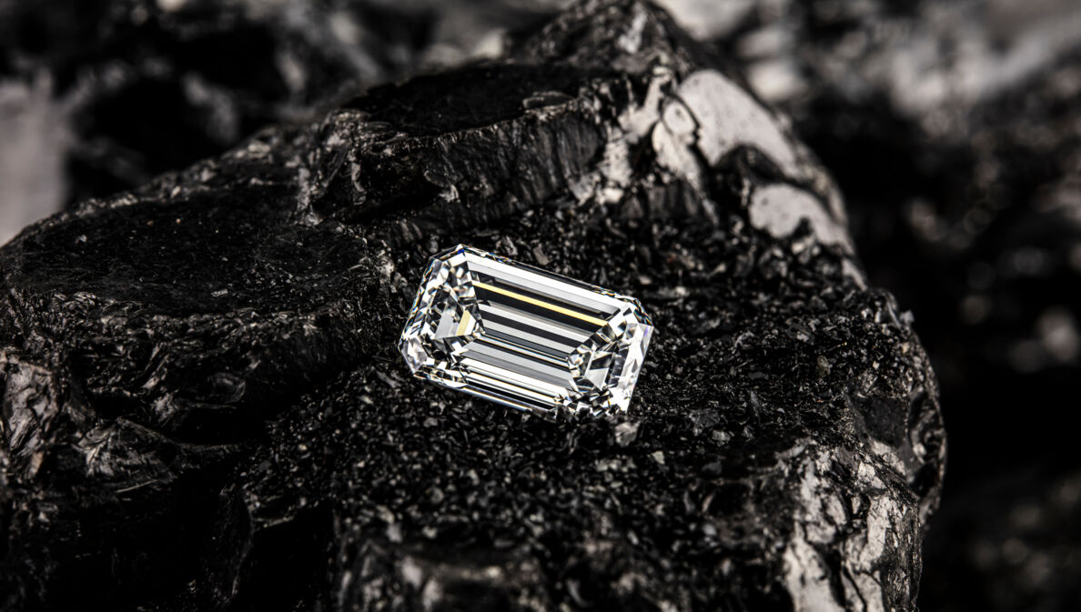 Einzelner Smaragddiamant auf schwarzem Kohlehintergrund.