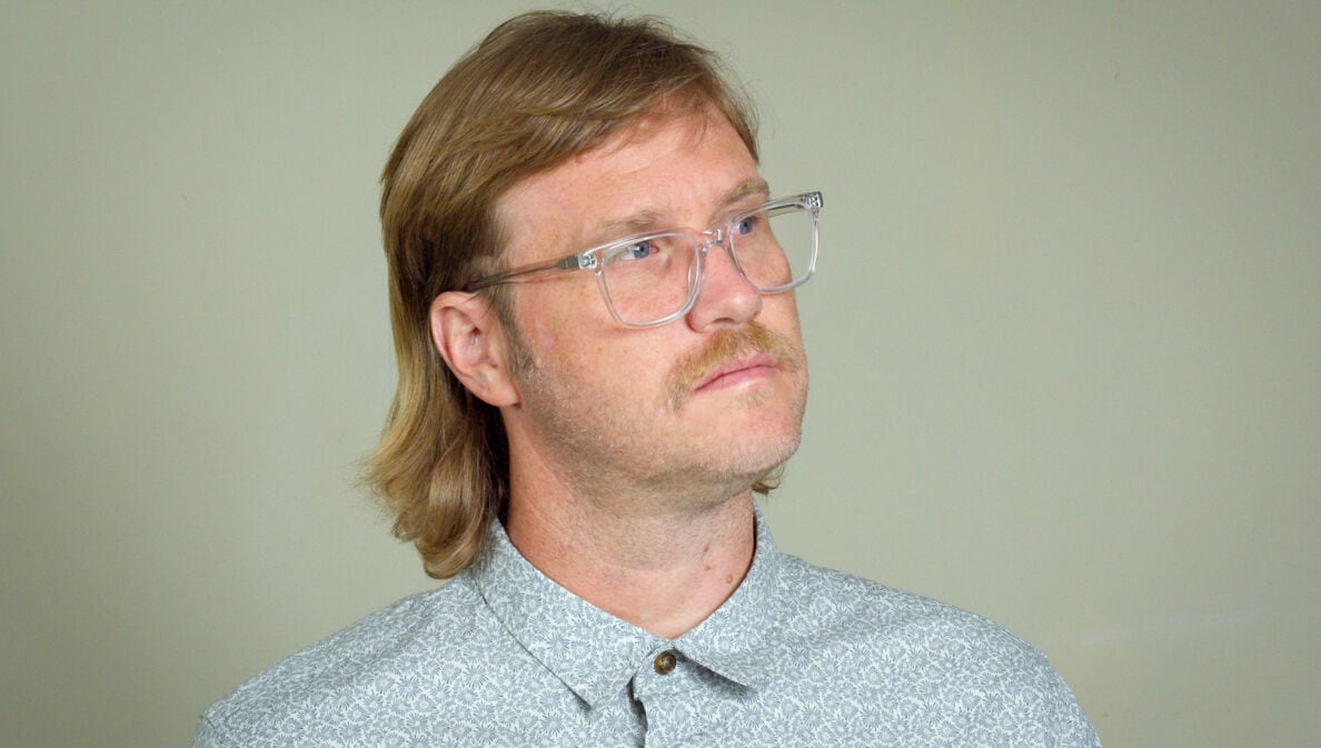 Ein Mann mit einem Mullet-Haarschnitt und Brille