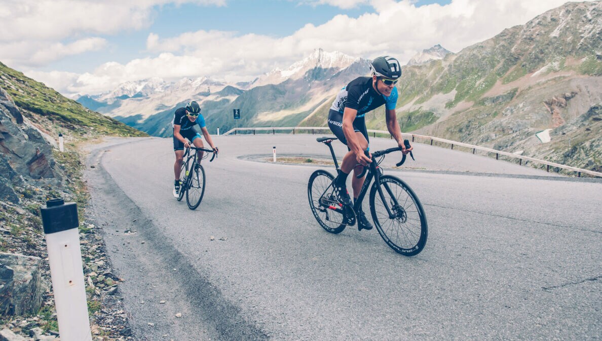 Zwei Rennradfahrer auf einer Bergstraße.