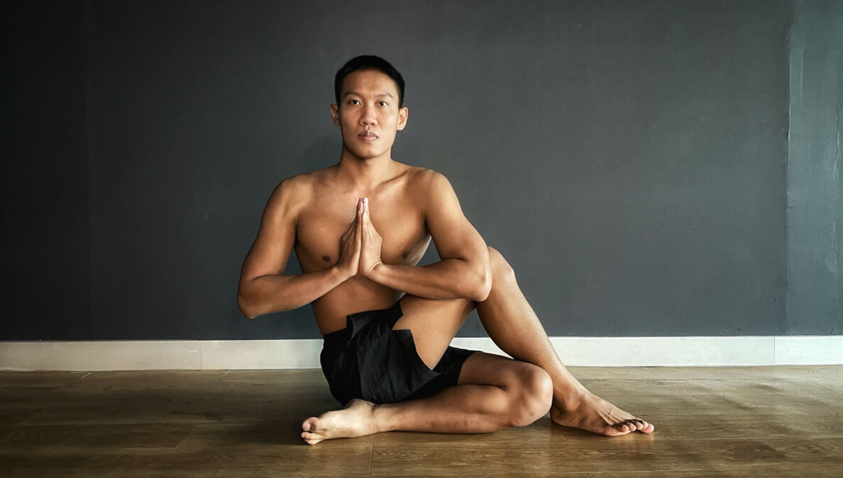 Mann macht Yoga, sitzt im halben Drehsitz