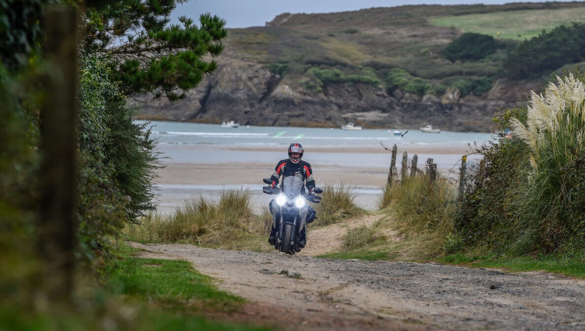 Ein Motorradfahrer auf einem Schotterweg an einer rauen Küste