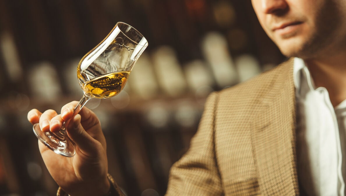 Ein Mann schwenkt ein Whisky Nosing Glas in seiner Hand