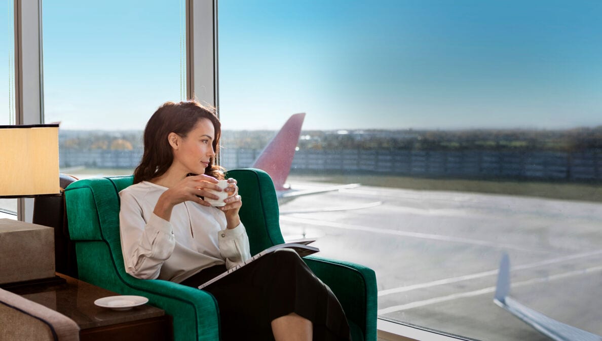 Eine Frau genießt in einer Airport-Lounge eine Tasse Kaffee