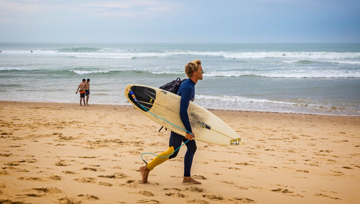 Ein Surfer mit Surfbrett an einem Strand