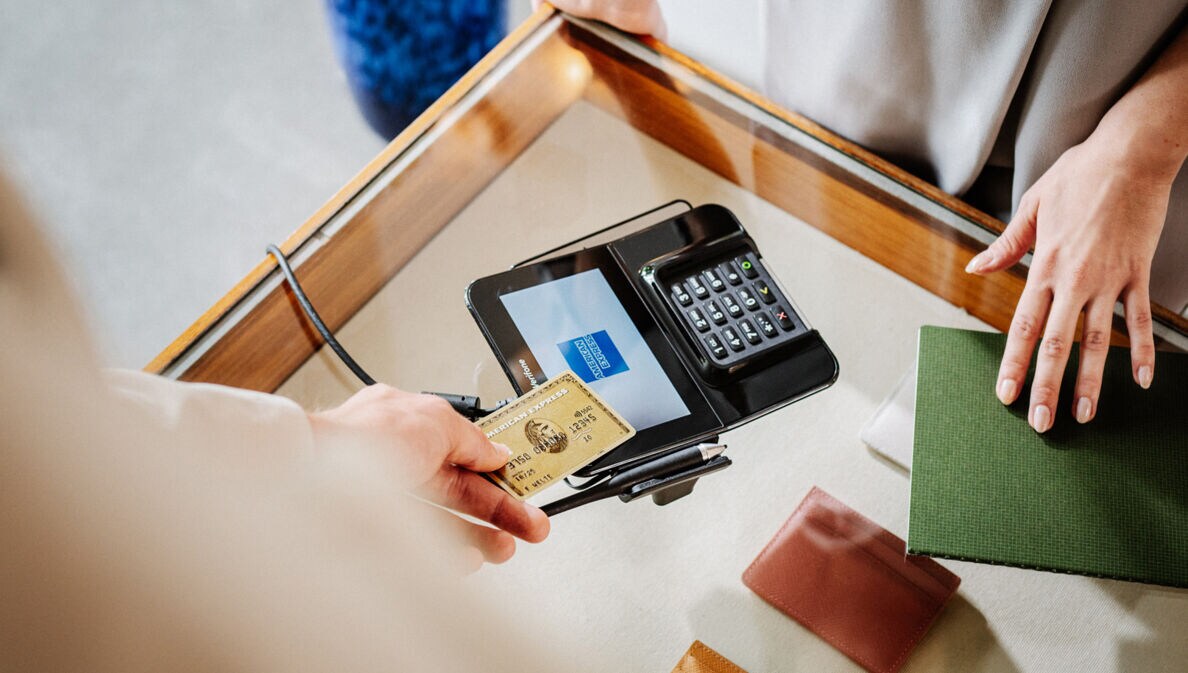 Eine Person zahlt in einer Amex Akzeptanzstelle kontaktlos mit Kreditkarte