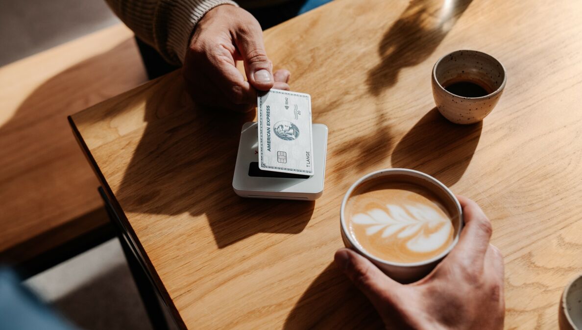 Kontaktlose Zahlung eines Cappuccinos mit einer silbernen Kreditkarte