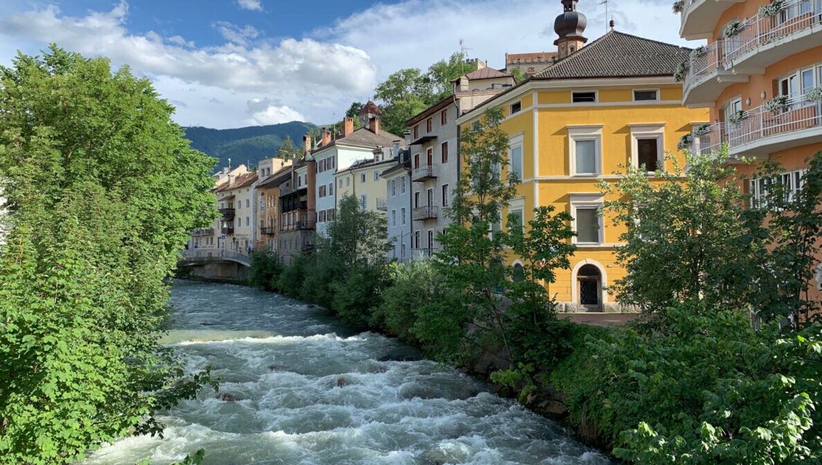 Ein Fluss verläuft inmitten von Gebäuden in Bruneck gegen den Himmel