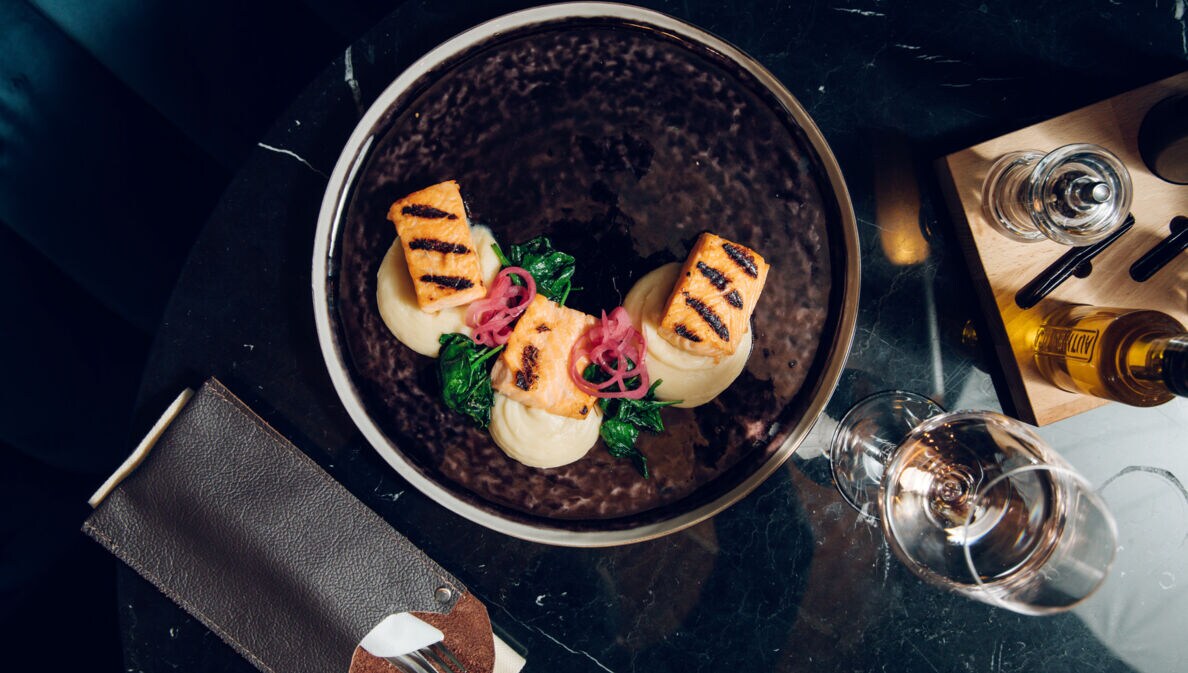 Exquisit angerichtete Speisen auf einem dunklen Teller, von oben fotografiert