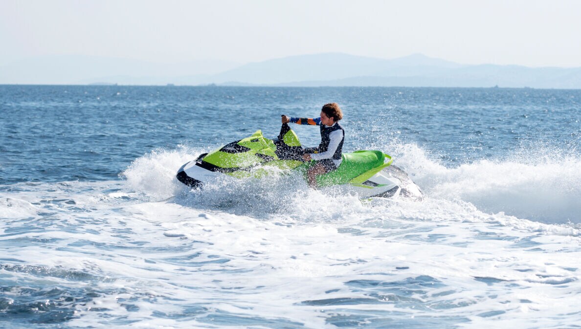 Eine Person fährt mit grünem Jetski auf dem offenen Meer