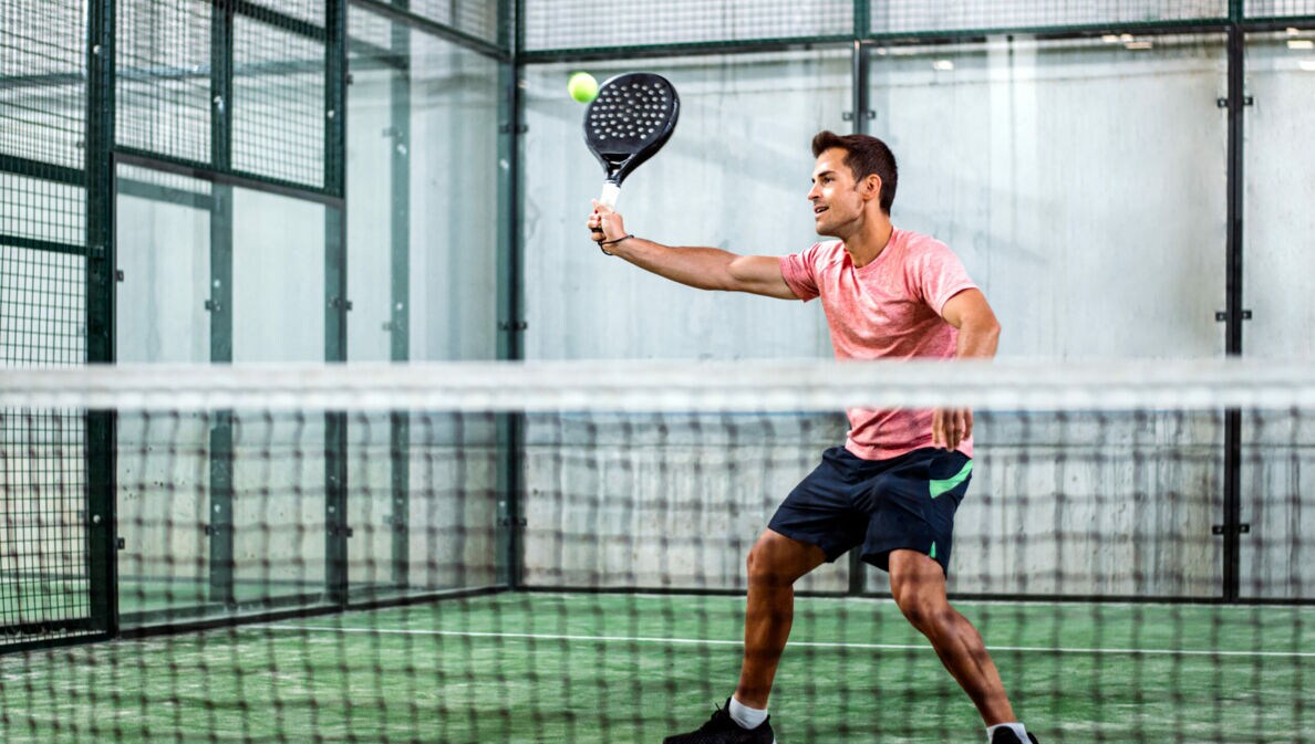 Ein Mann spielt Padel-Tennis in der Halle.