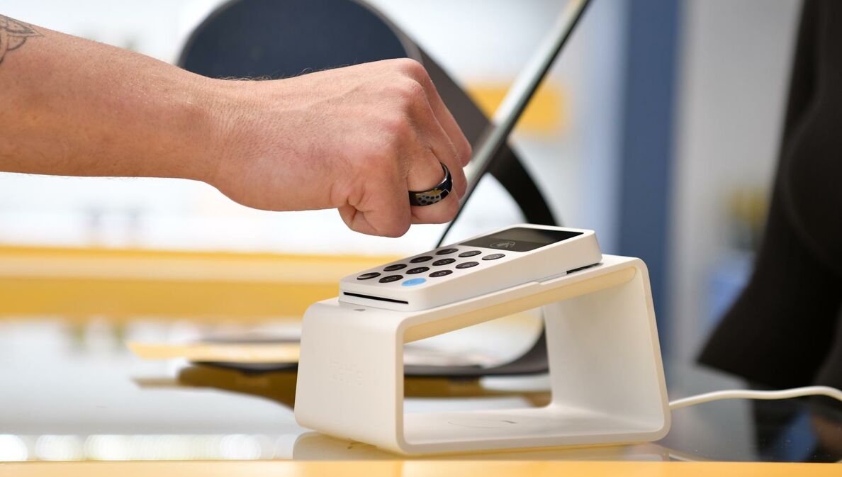 Eine Hand mit dunklem NFC-Ring beim kontaktlosen Bezahlen