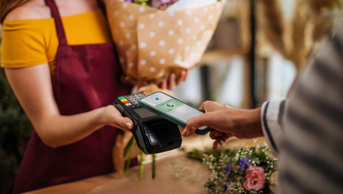Kontaktlose Zahlung mit American Express Kreditkarte per Smartphone in einer Boutique