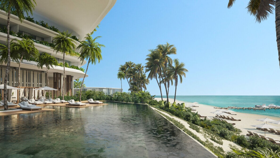 Poolbereich eines luxuriösen Hotels, mit Palmen gesäumt und Strandabschnitt im Hintergrund
