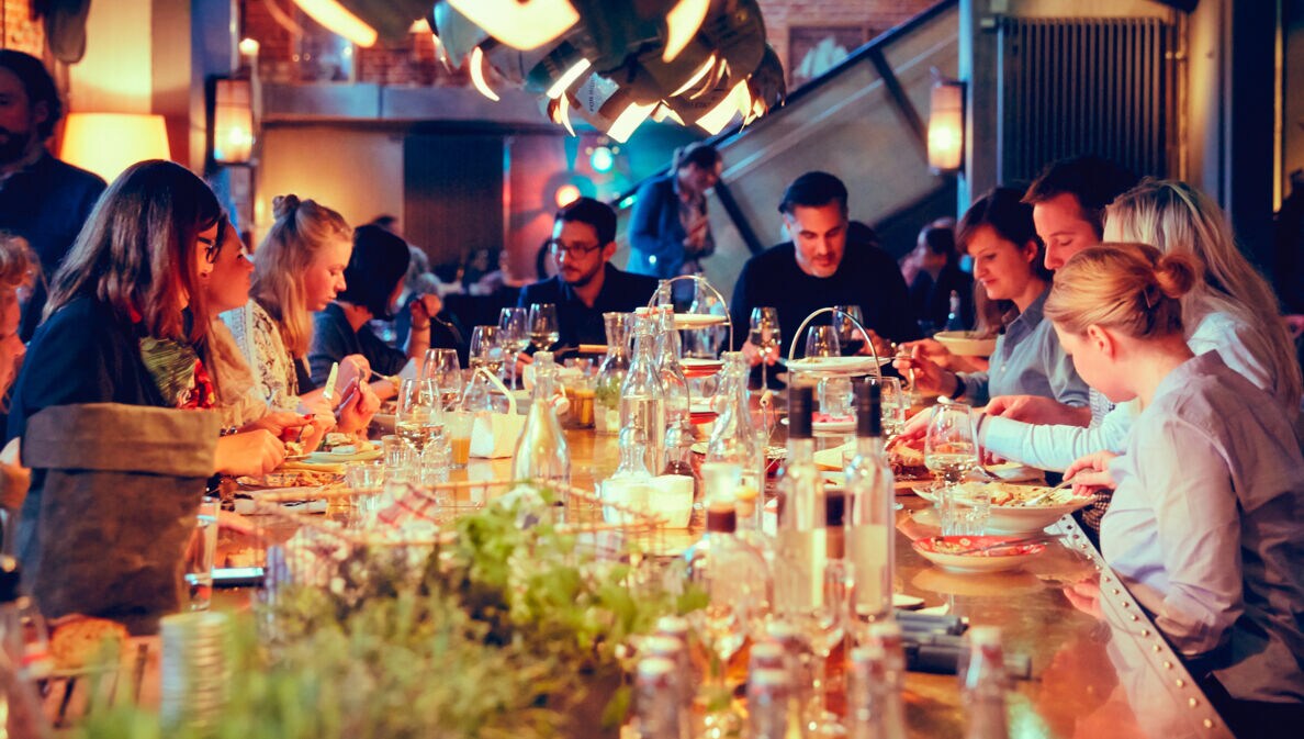 Eine große gesellige Menschengruppe sitzt an einem Tisch und isst zusammen.