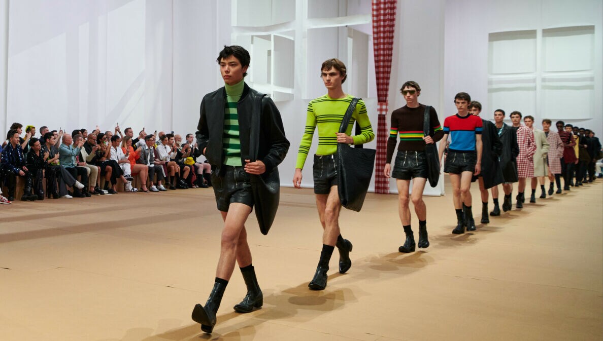 Männliche Models in Ledershorts laufen in Reihe auf einem Catwalk