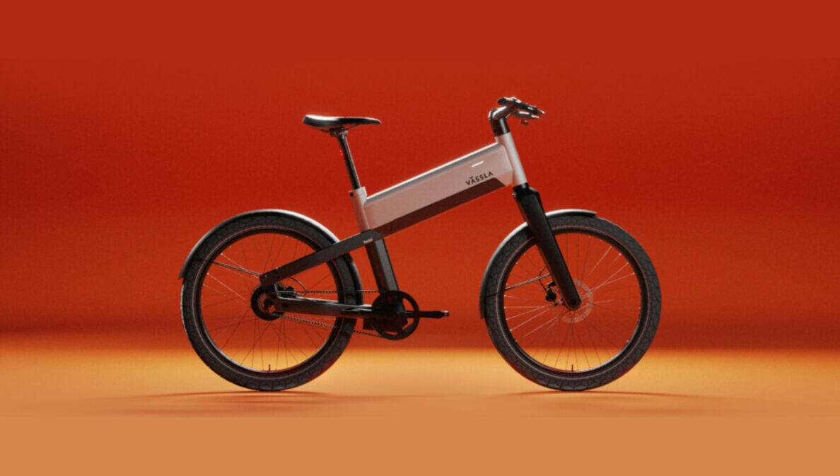 Ein schwarz-silbernes E-Bike der Marke Vässla vor rot-orangenem Hintergrund