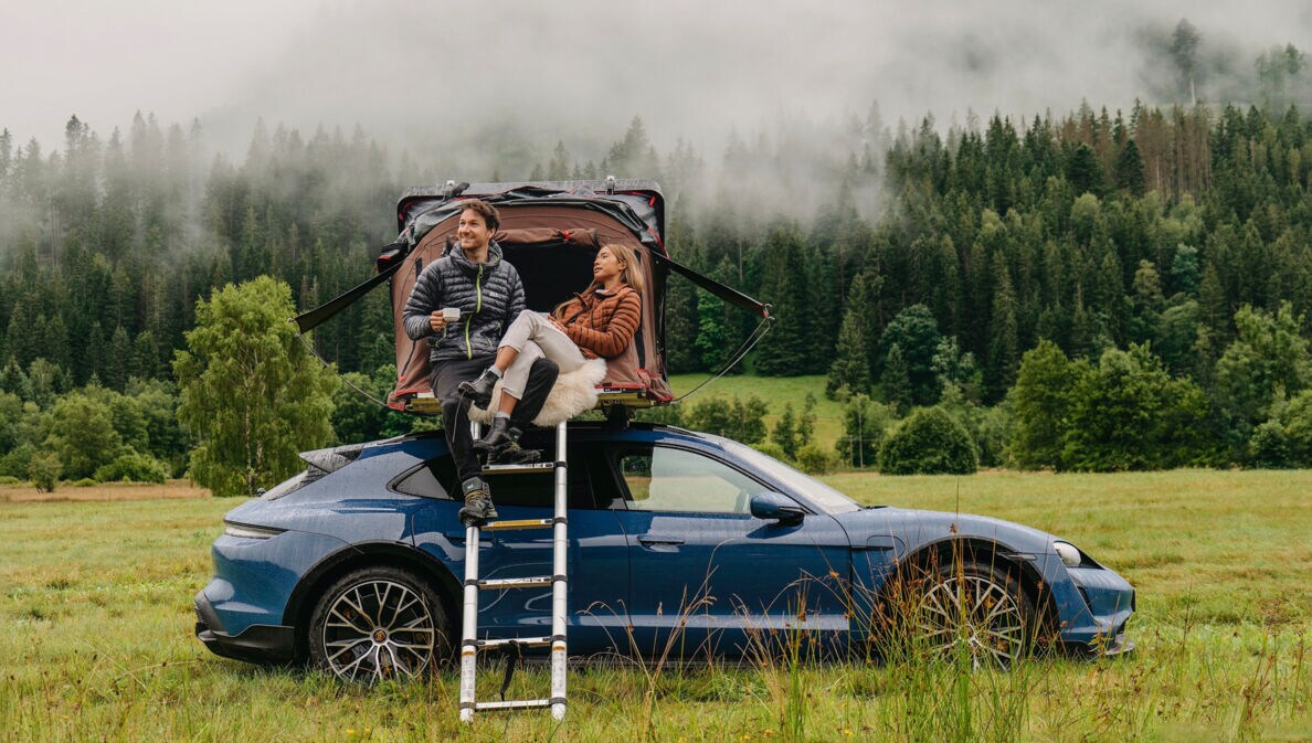 Eine Frau und ein Mann an einem Auto mit Dachzelt