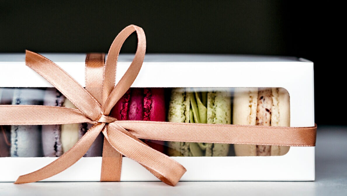 Eine Packung Macarons, dekoriert mit einem beigen Geschenkband