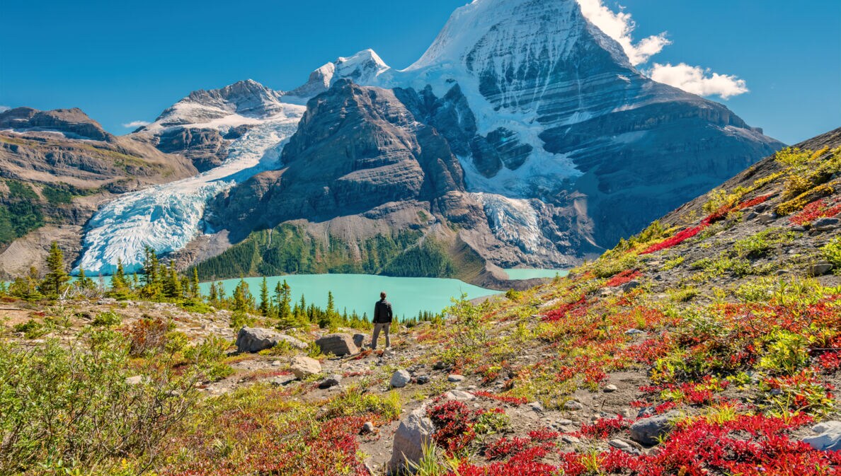 Ein Wanderer steht an einem See im Gebirge eines Nationalparks in Kanada