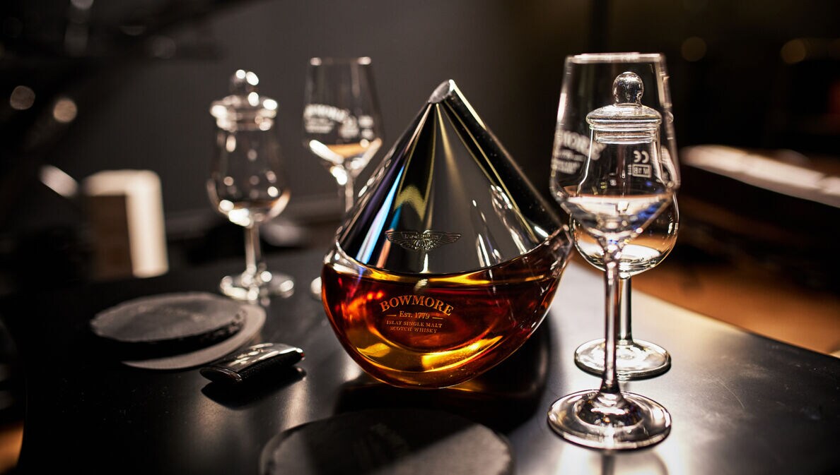 Eine Flasche Bowmore ARC-52 aus der Kooperation mit Aston Martin steht auf einem Tisch mit speziellen Whisky-Gläsern