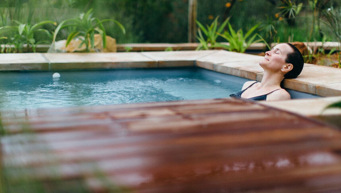 Eine Frau liegt entspannt in einem Whirlpool in der Natur