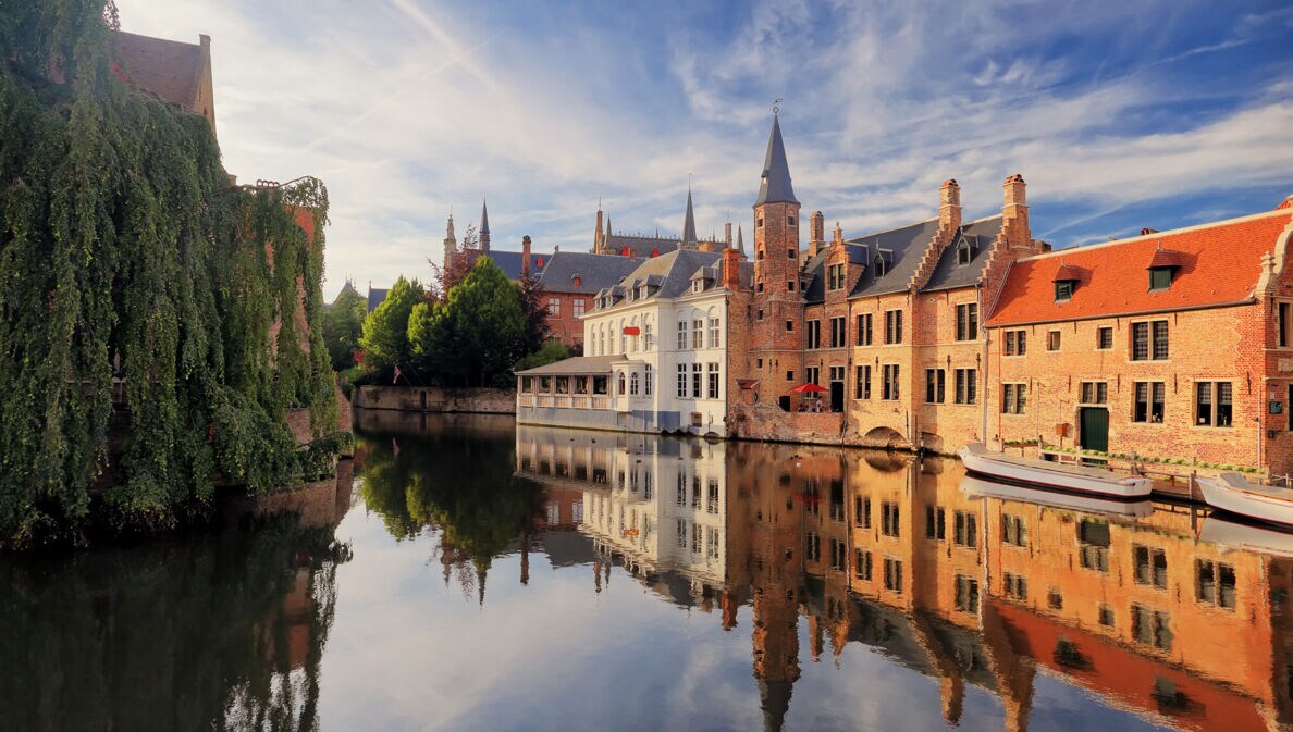 Historisches Zentrum von Brügge mit mittelalterlichen Gebäuden, die sich im Wasser spiegeln.